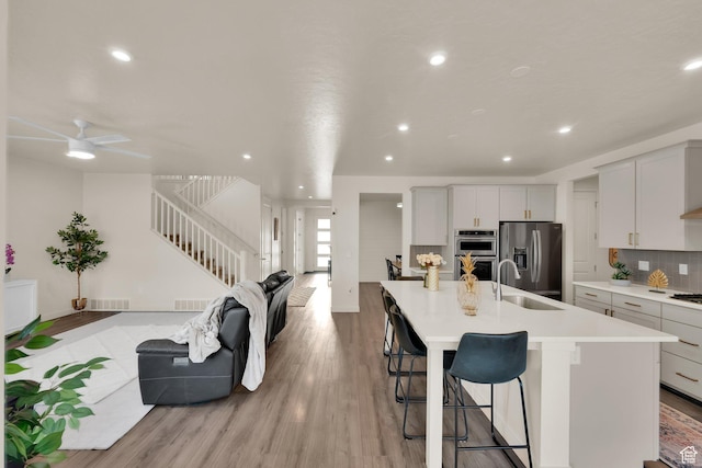 977 S 1480 W, Provo, UT 84601 - kitchen featuring a sink, open floor plan, stainless steel appliances, light wood-style flooring, and decorative backsplash