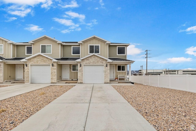 view of front of home featuring driveway, stone siding, fence, and board and batten siding
