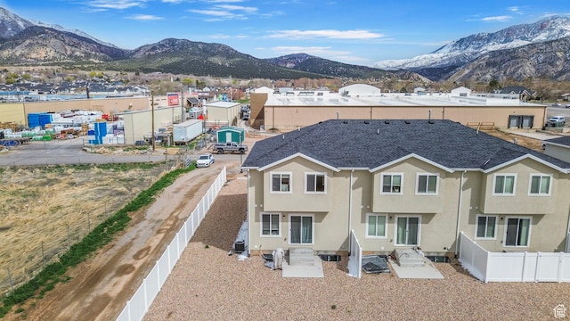 rear view of property with fence, stucco siding, and a mountain view