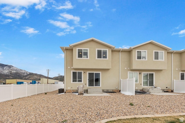 back of property with central air condition unit, a fenced backyard, stucco siding, entry steps, and a mountain view