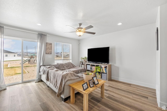living area with baseboards, recessed lighting, light wood-style flooring, a textured ceiling, and ceiling fan