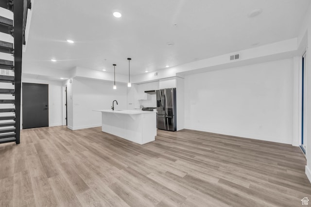 933 S Washington St Unit 107, Salt Lake City, UT 84101 - kitchen featuring stainless steel fridge with ice dispenser, light wood-type flooring, visible vents, a sink, and open floor plan