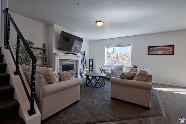 living room featuring baseboards, a brick fireplace, a textured ceiling, wood finished floors, and stairs
