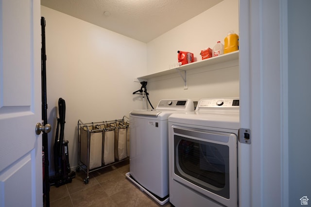 laundry area with dark tile patterned floors, washing machine and dryer, and laundry area