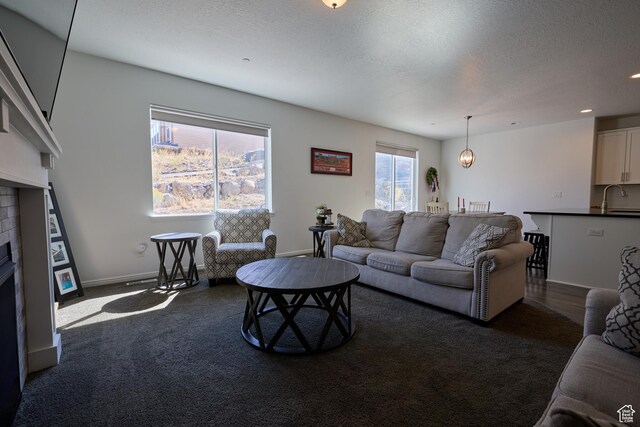 living area featuring carpet floors, baseboards, a textured ceiling, and a fireplace