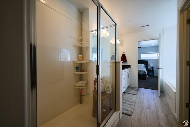 full bath with visible vents, a shower stall, ensuite bath, vanity, and a garden tub