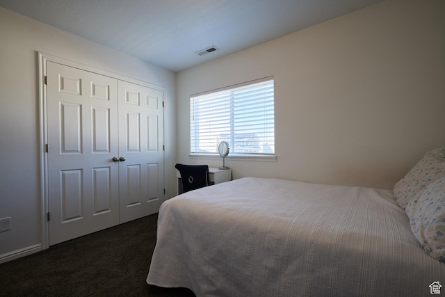 bedroom with dark carpet, a closet, and visible vents