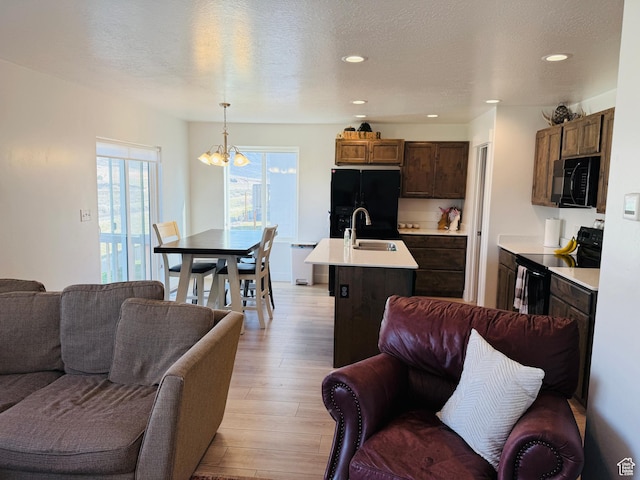 living area with recessed lighting, light wood finished floors, a textured ceiling, and an inviting chandelier