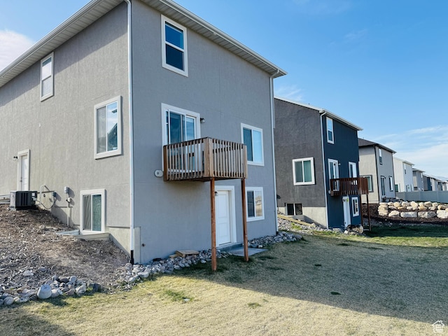 rear view of house featuring stucco siding, a balcony, and central air condition unit