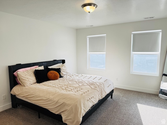 carpeted bedroom featuring visible vents, multiple windows, and baseboards