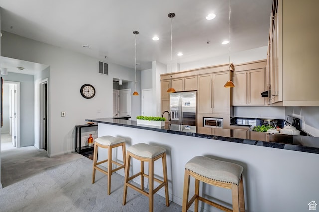 kitchen featuring a peninsula, visible vents, light carpet, dark countertops, and stainless steel fridge