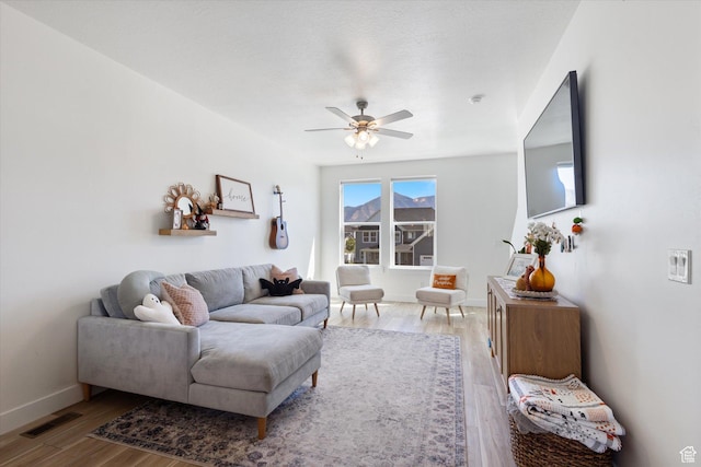 living room with wood finished floors, ceiling fan, baseboards, and visible vents