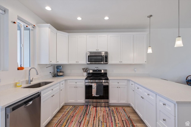 kitchen featuring a sink, light wood-style floors, appliances with stainless steel finishes, and a peninsula