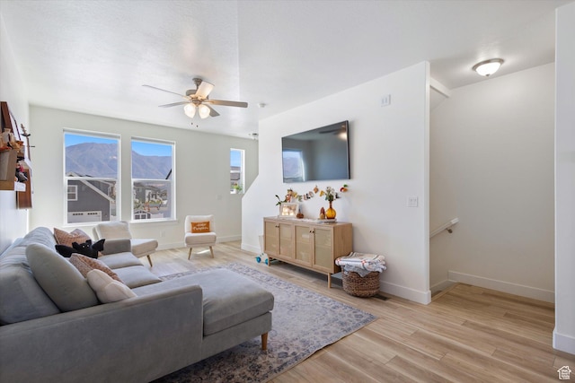 living area featuring light wood finished floors, baseboards, and a ceiling fan