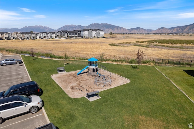 exterior space with fence, a mountain view, and a playground