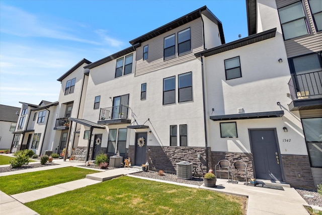 townhome / multi-family property featuring a residential view, cooling unit, stucco siding, and stone siding