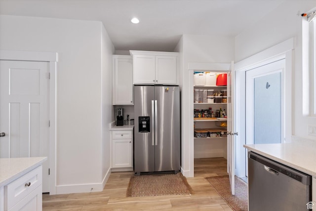 kitchen featuring white cabinetry, light countertops, light wood-style flooring, and appliances with stainless steel finishes