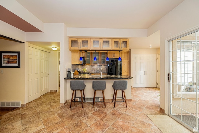 2356 E 3900 S, Millcreek, UT 84124 - kitchen with black refrigerator with ice dispenser, tasteful backsplash, a kitchen bar, a peninsula, and light stone finish floors