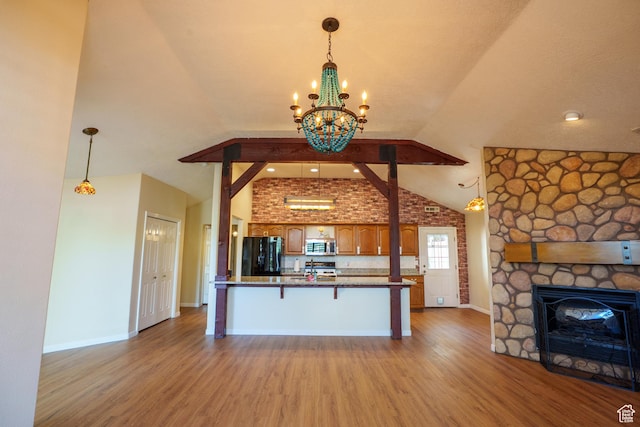 kitchen featuring stainless steel microwave, light wood-style floors, black refrigerator, and open floor plan