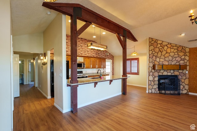 kitchen featuring white gas range, wood finished floors, a sink, a breakfast bar area, and stainless steel microwave