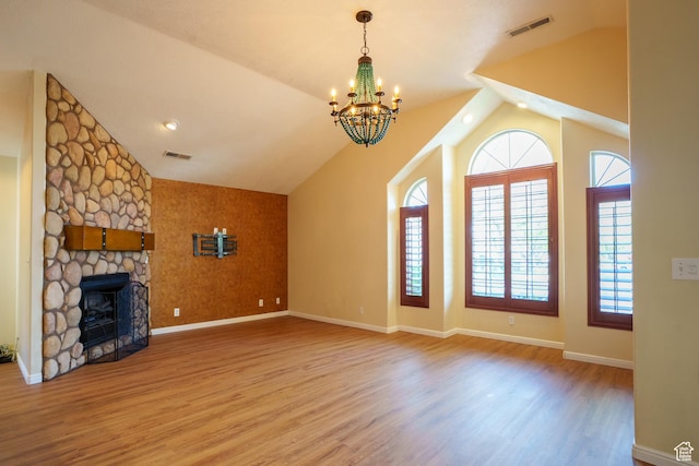 unfurnished living room with vaulted ceiling, visible vents, wood finished floors, and an inviting chandelier