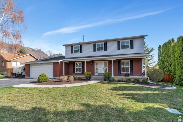 traditional home with an attached garage, aphalt driveway, brick siding, a front yard, and covered porch