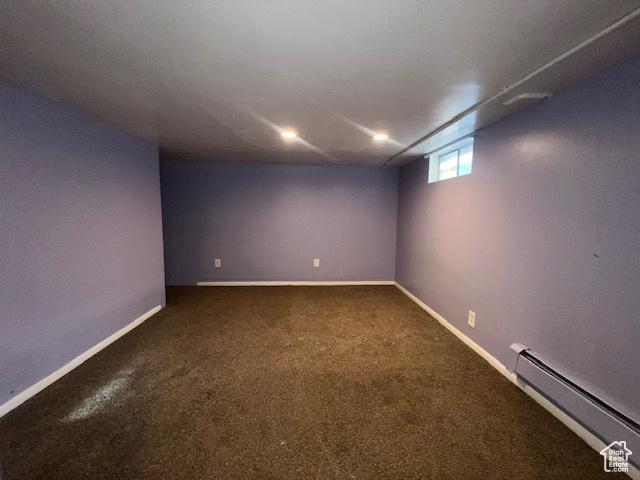 below grade area featuring a baseboard heating unit, baseboards, and carpet floors