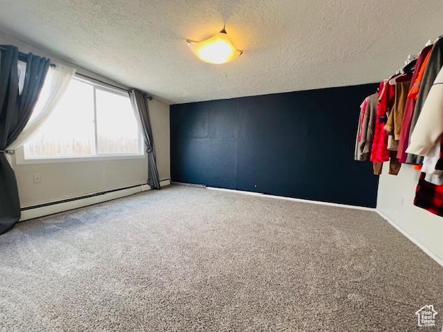 carpeted empty room with baseboard heating and a textured ceiling