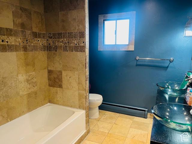 full bath featuring double vanity, tile patterned flooring, toilet, a baseboard radiator, and a sink