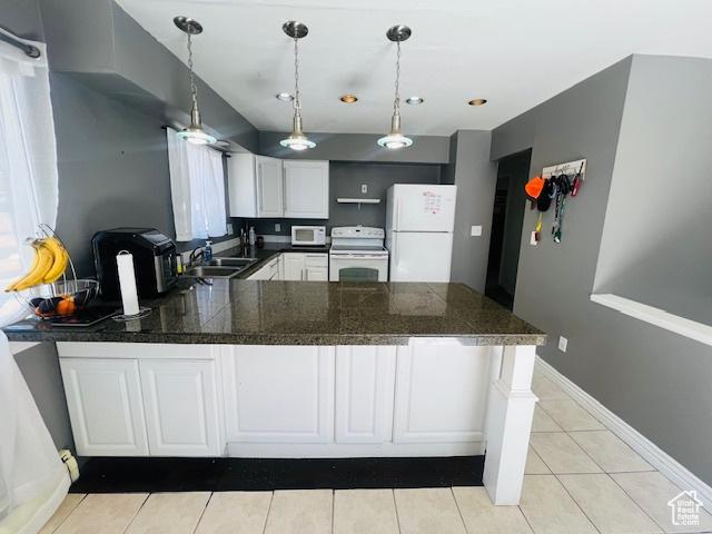kitchen featuring a sink, tile countertops, white appliances, and a peninsula