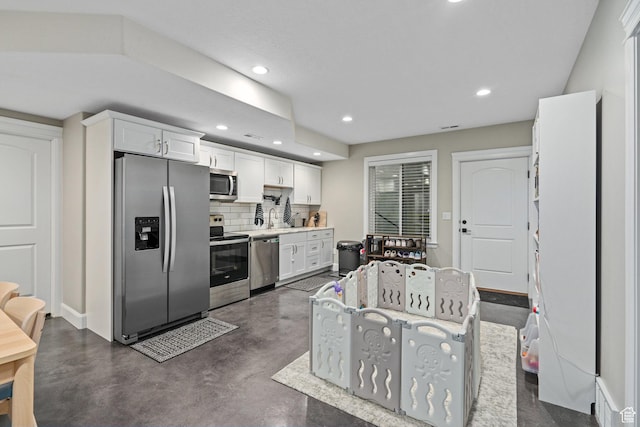 kitchen featuring tasteful backsplash, white cabinetry, recessed lighting, appliances with stainless steel finishes, and a sink