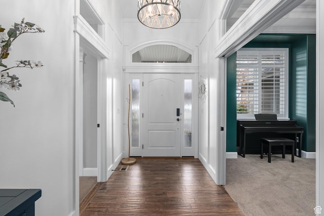 foyer featuring carpet, hardwood / wood-style floors, an inviting chandelier, and baseboards