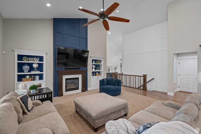 living area with high vaulted ceiling, a fireplace, a ceiling fan, recessed lighting, and built in shelves