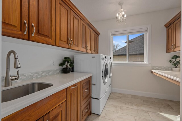 laundry area featuring separate washer and dryer, baseboards, cabinet space, marble finish floor, and a sink