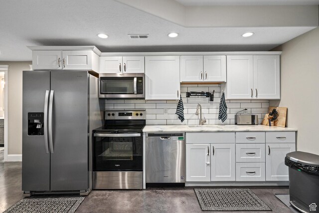 kitchen featuring tasteful backsplash, white cabinets, visible vents, a sink, and stainless steel appliances