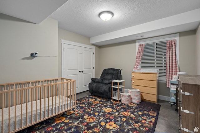 bedroom with a closet, finished concrete floors, a textured ceiling, and baseboards