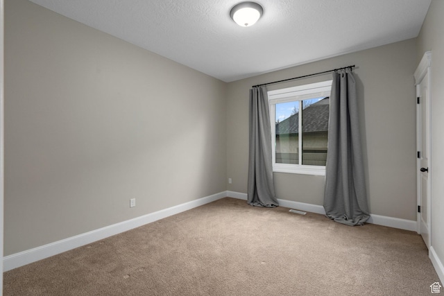 carpeted empty room featuring visible vents, baseboards, and a textured ceiling