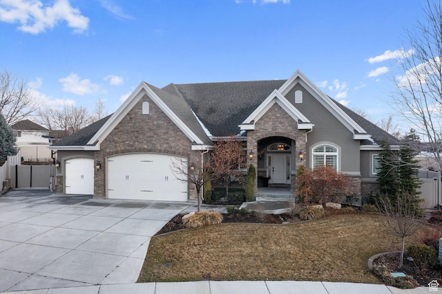 view of front facade featuring an attached garage, stone siding, fence, a gate, and driveway