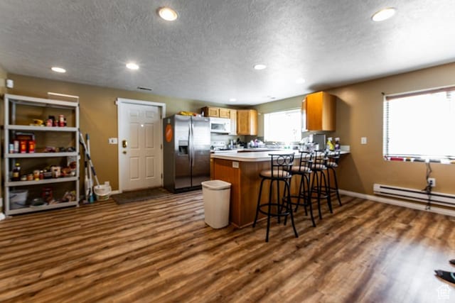 kitchen featuring a baseboard radiator, a textured ceiling, stainless steel fridge with ice dispenser, white microwave, and dark wood-style floors