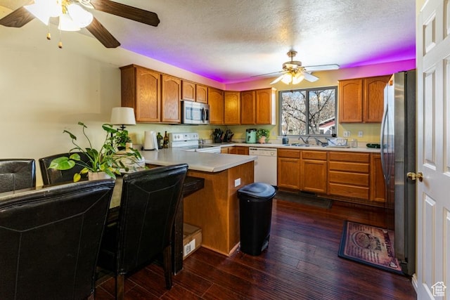 kitchen featuring ceiling fan, a peninsula, appliances with stainless steel finishes, and brown cabinets