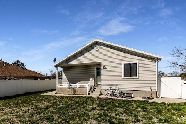 rear view of house featuring fence, a lawn, entry steps, and a gate