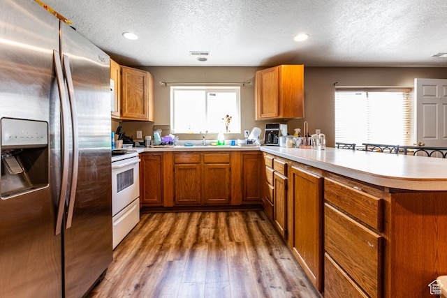 kitchen featuring a peninsula, stainless steel fridge with ice dispenser, white electric stove, and a textured ceiling