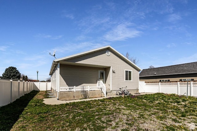 rear view of house featuring a lawn and a fenced backyard