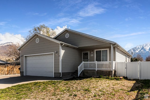 ranch-style home featuring fence, an attached garage, driveway, a porch, and a mountain view