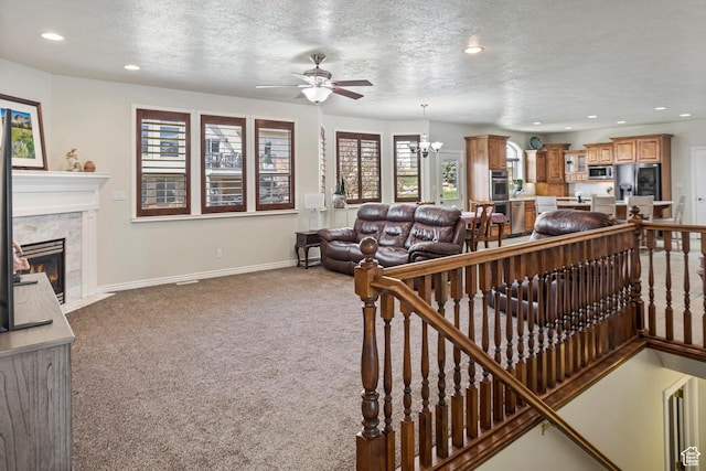 living room featuring recessed lighting, a tiled fireplace, a textured ceiling, carpet flooring, and ceiling fan with notable chandelier