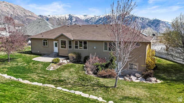 back of property with a lawn, a patio, stucco siding, and a mountain view