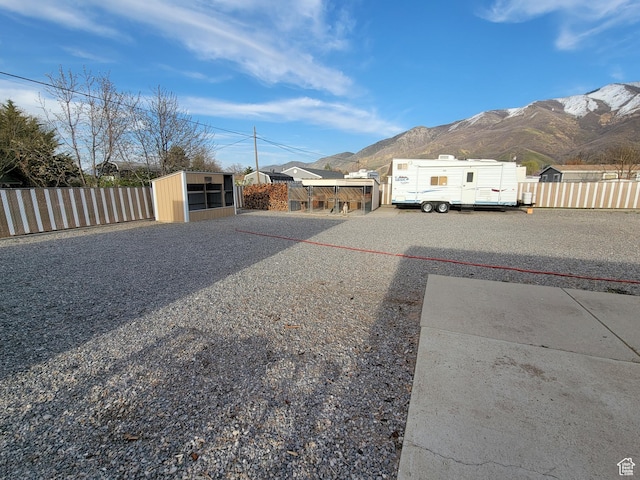 view of yard featuring an outdoor structure, a mountain view, fence, and a shed