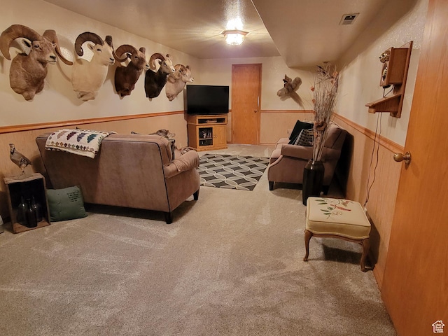 living room with a wainscoted wall, visible vents, and carpet