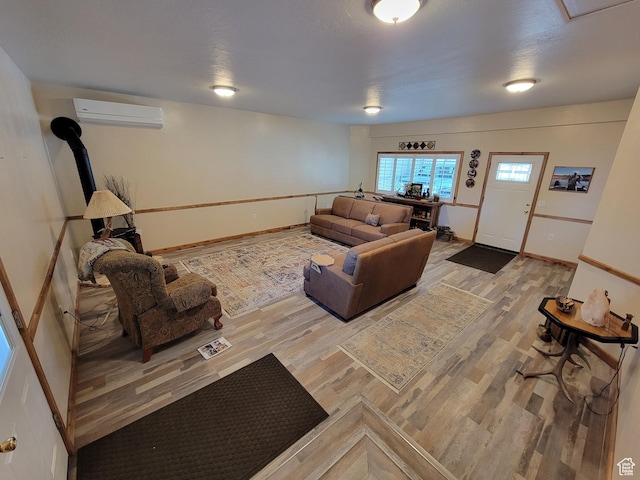 living room featuring a wall mounted air conditioner, baseboards, a wood stove, and light wood finished floors