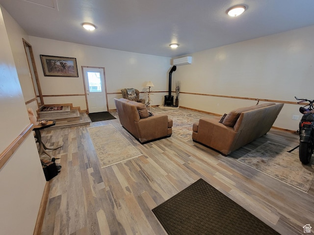 living room featuring baseboards, wood finished floors, a wood stove, and a wall mounted air conditioner